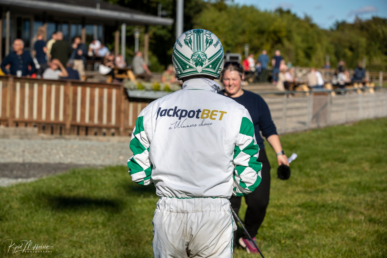 Flemming Jensen gör reklam för Jackpotbet i Danmark (bilden), medan han kör i en dress med Jackpot Club på ryggen när han tävlar i Sverige. Båda dressarna är godkända i respektive land. Foto: Kjeld Mikkelsen/KM Foto